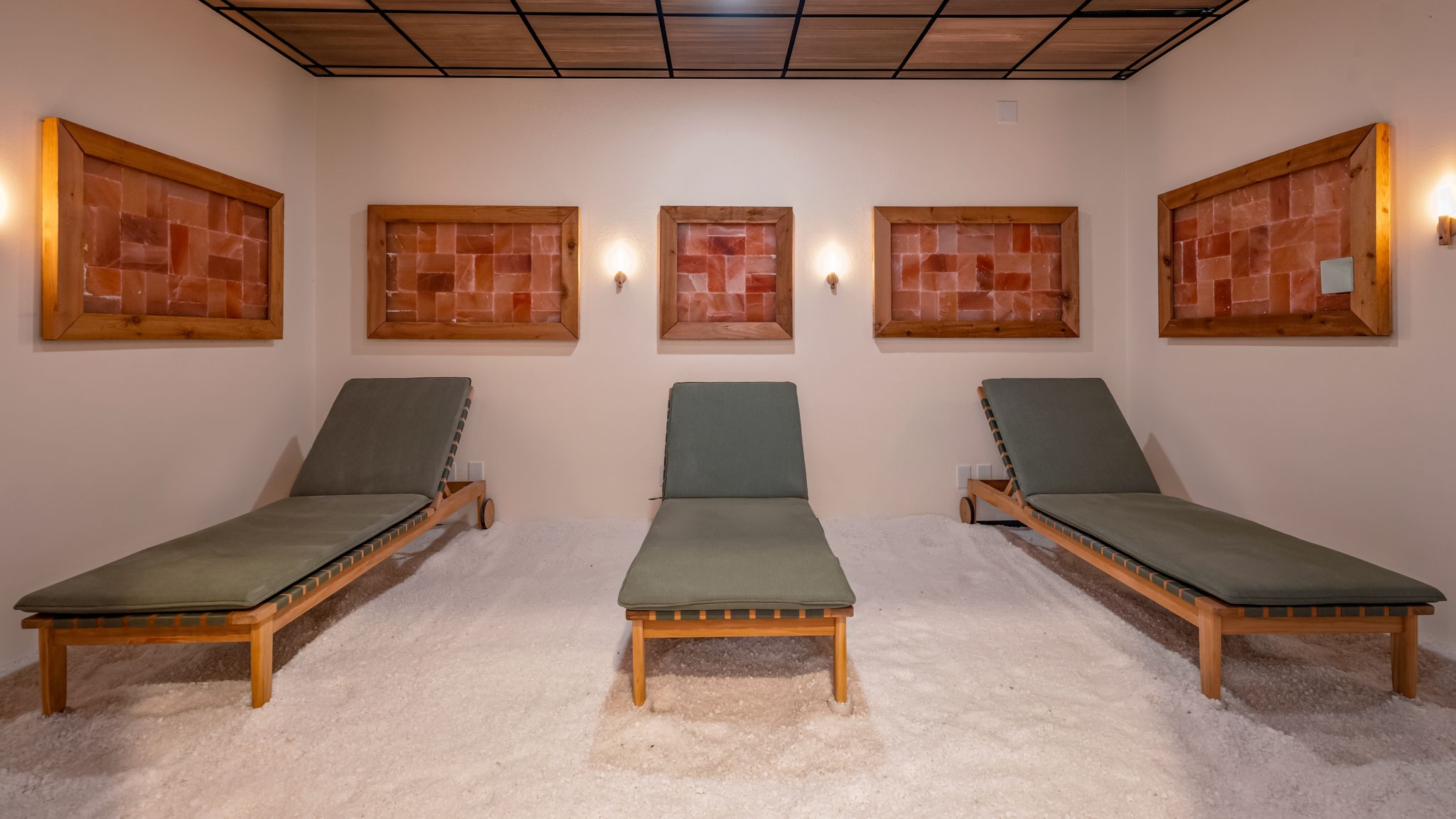 Three padded lounge chairs sit beneath framed artworks in a softly lit room.