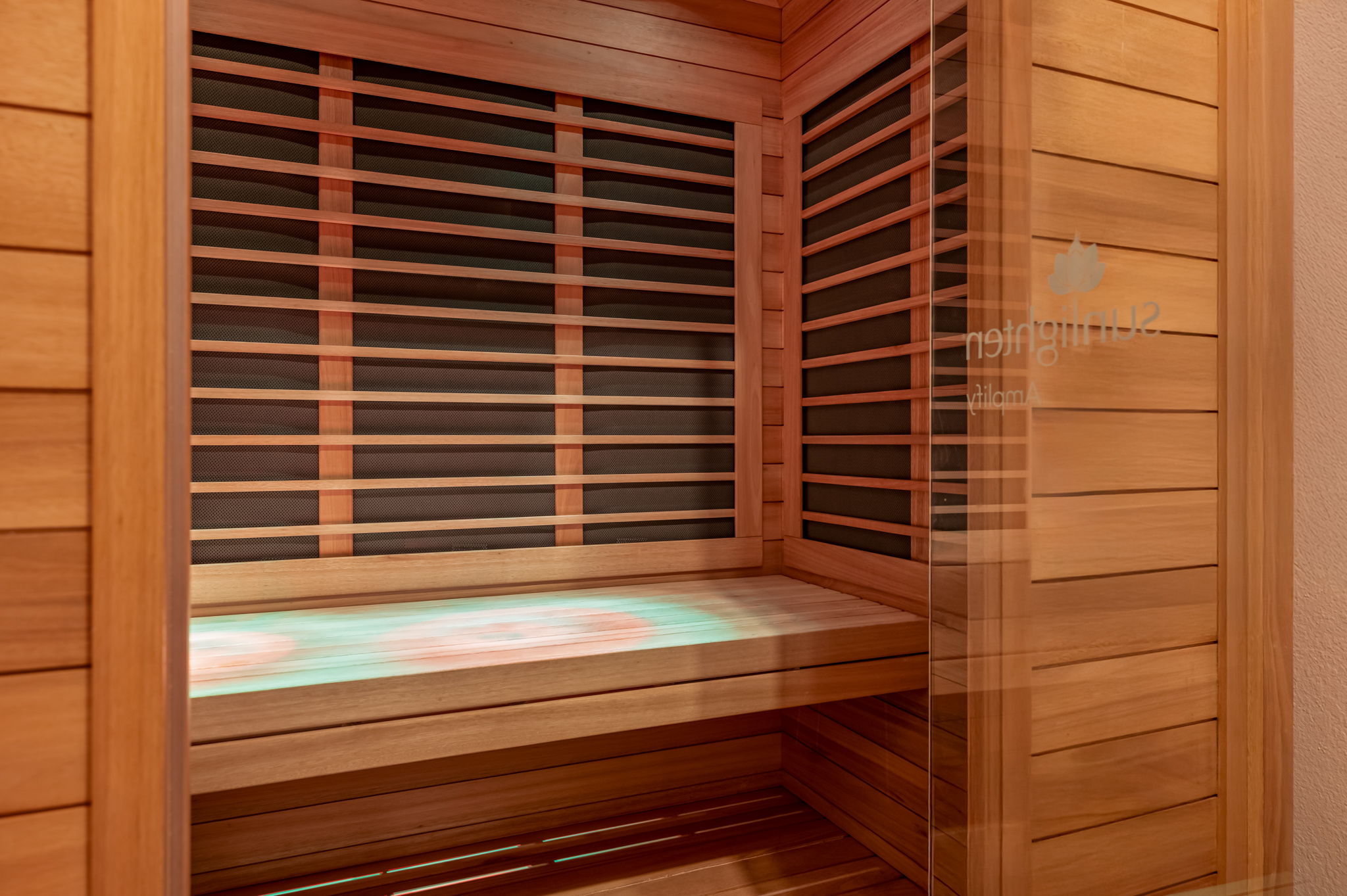Wood-paneled sauna with a slatted bench and horizontal wooden wall slats.