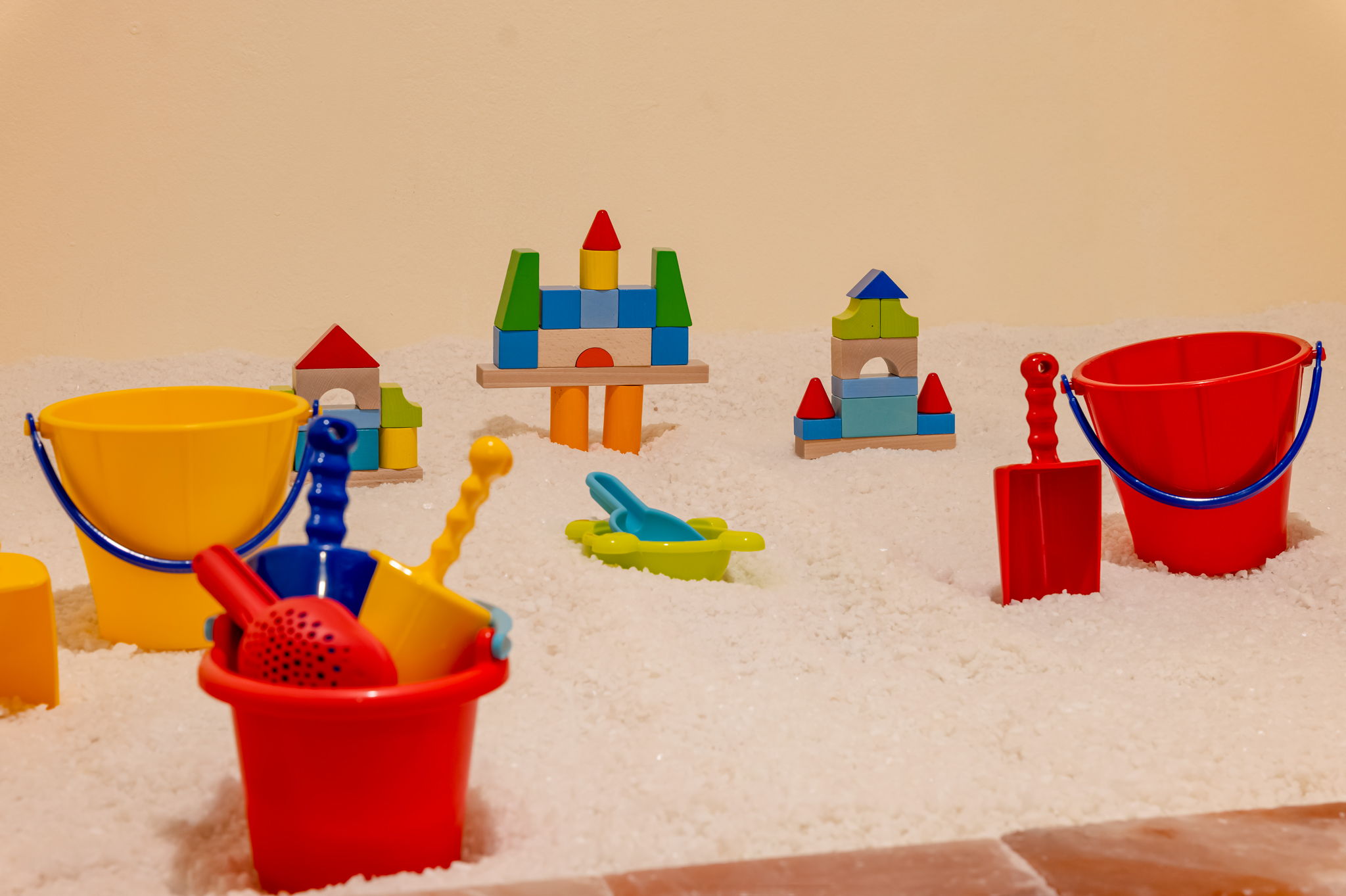 Colorful plastic sand toys, including buckets, shovels, and toy castles, arranged in a sandbox.