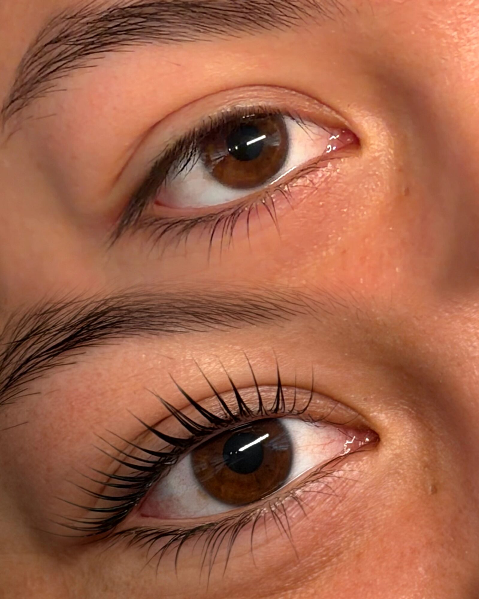 Close-up of two eyes, with the lower eye showing long, dark eyelashes.