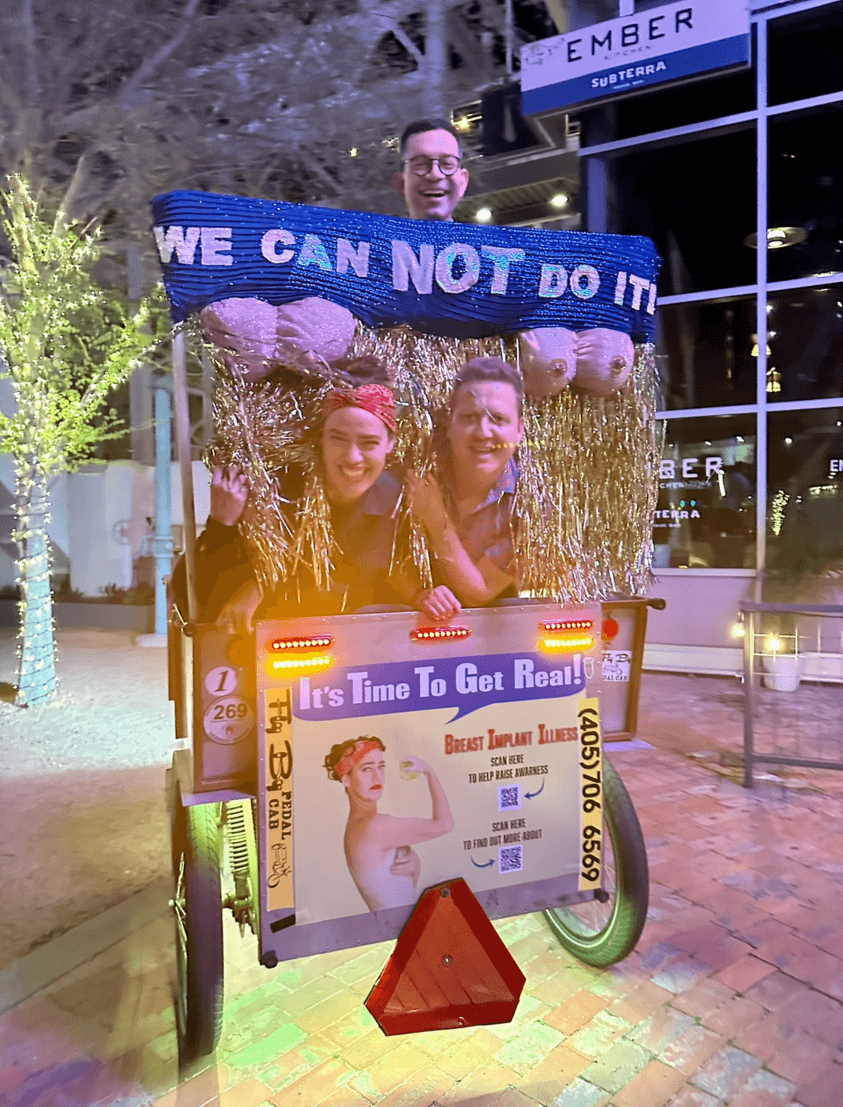 A decorated promotional cart displays a banner reading “WE CAN NOT DO IT” and a poster beneath a framed photo.