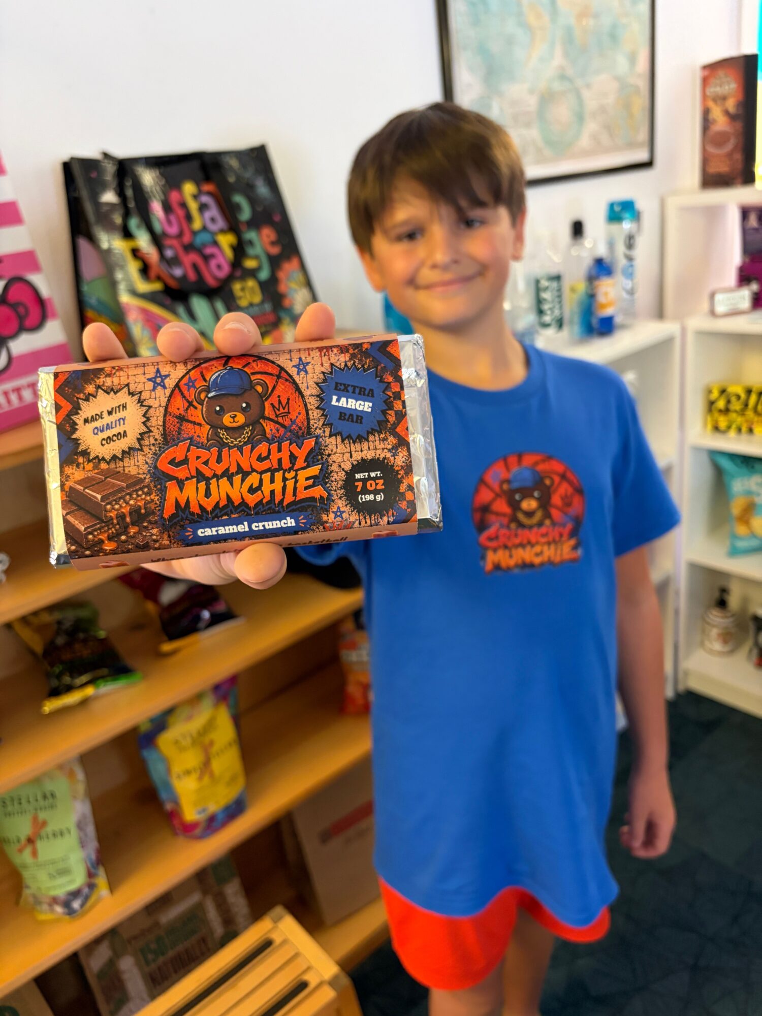 A person in a blue shirt holds a colorful chocolate bar box in a shop.