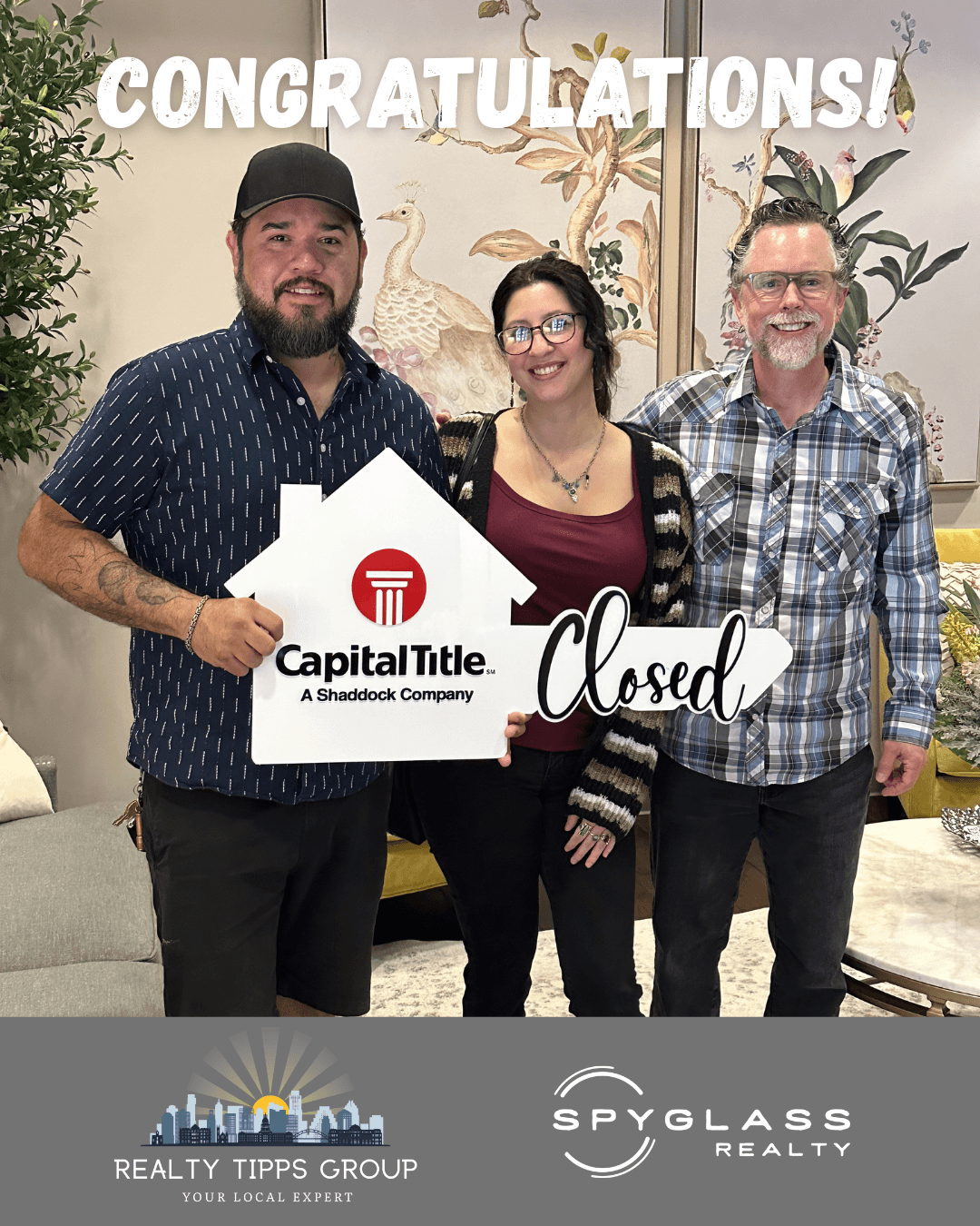 Three people stand together holding a large house-shaped sign reading “Capital Title” and “Closed,” beneath a congratulations banner.