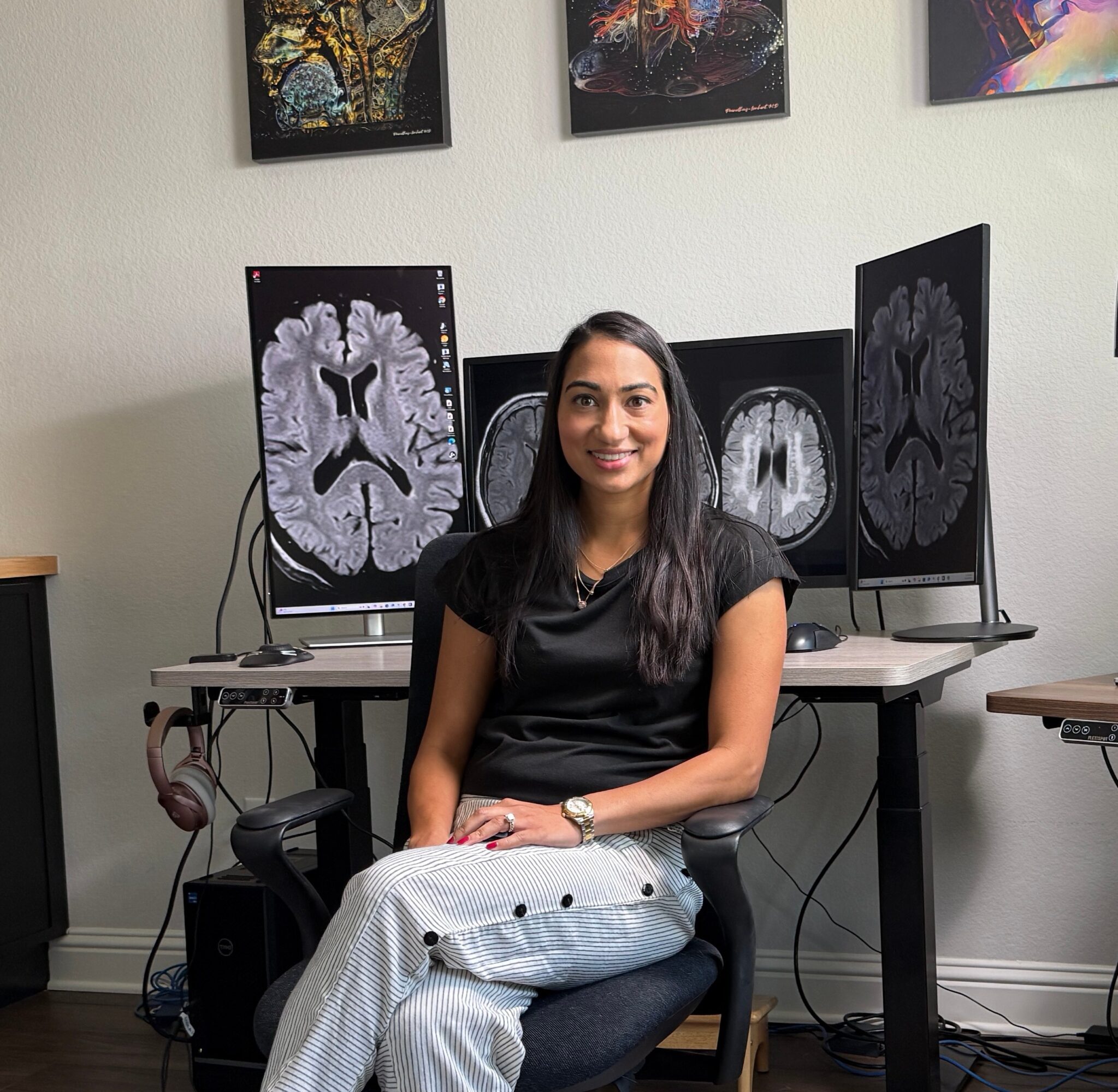 A seated person in front of several medical brain scan images displayed on monitors and wall panels.