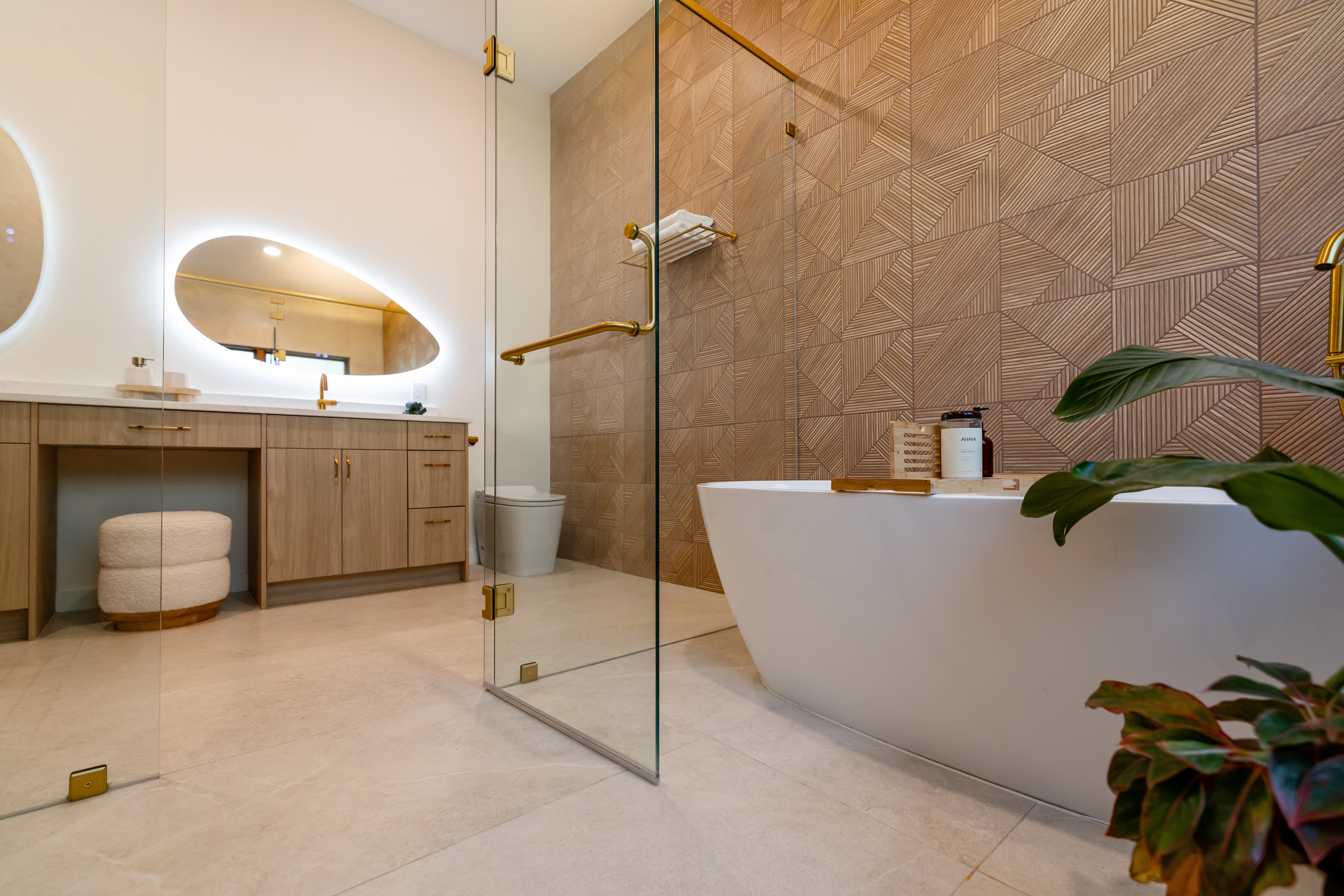 Modern bathroom with a freestanding bathtub, glass shower panel, wooden vanity, and leafy plants.