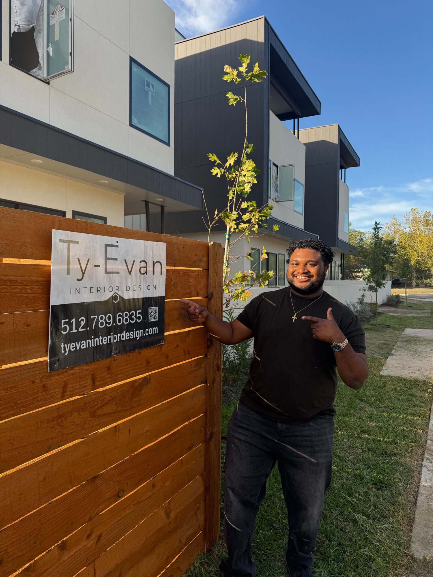 Person standing beside a wooden gate in front of a modern house.